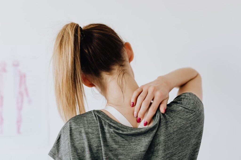 pexels-photo-4506105 A woman in casual clothing holds her neck, indicating pain or discomfort.